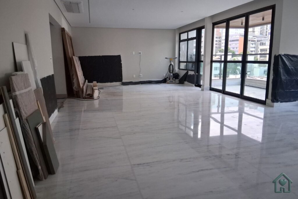 Uma sala de estar de apartamento recém-reformado e impecavelmente limpa, com design moderno e toques de design biofílico (plantas naturais). A luz do sol entra por grandes janelas de esquadrias de alumínio preto, refletindo em um piso de porcelanato polido sem nenhum traço de poeira. A atmosfera transmite paz, alívio e conforto visual. Estilo fotorrealista, 8k, iluminação natural suave.